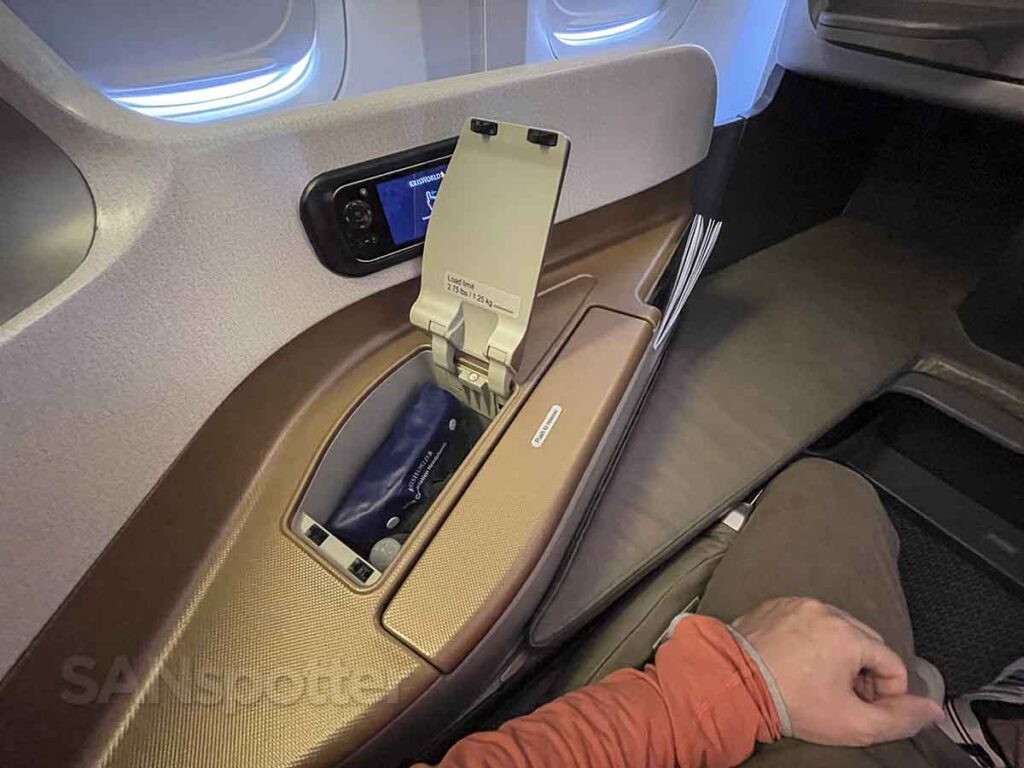 Armrest storage space containing a full bottle of water and noise canceling headphones